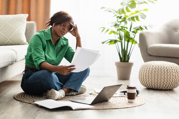 Stressed African Woman Holding Papers Sitting At Laptop At Home - obrazy, fototapety, plakaty