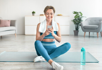 Fitness lady using phone during workout break