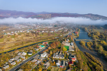 Thick fog in the morning at dawn. Fog enveloped the forest and mountains over the village. View from above.