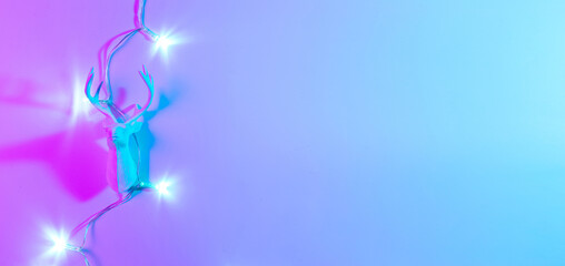 Stylish Christmas neon winter background. Holiday decoration bauble ball on neon gradient backdrop. Minimal abstract xmas reindeer. Happy new year copy space.