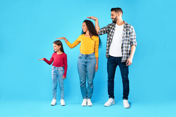Arabic Parents And Daughter Posing Measuring Each Other's Height, Studio