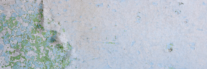 Peeling paint on the wall. Panorama of a concrete wall with old cracked flaking paint. Weathered rough painted surface with patterns of cracks and peeling. Wide panoramic grungy texture for background