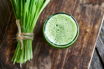 A glass of green barley grass juice with fresh barley grass