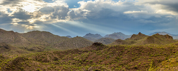 Aerial drone panorama image of a monsoon over the Sonoran Desert of Arizona with dramatic lighting and rugged terrain.