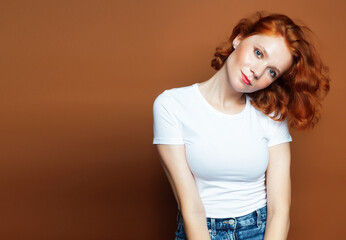 young pretty redhead girl posing cheerful on warm brown background, lifestyle people concept