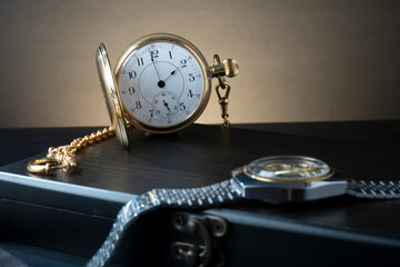 Closeup of vintage pocket watch and wristwatches against studio background.