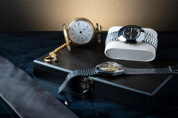 Closeup of vintage pocket watch and wristwatches against studio background.