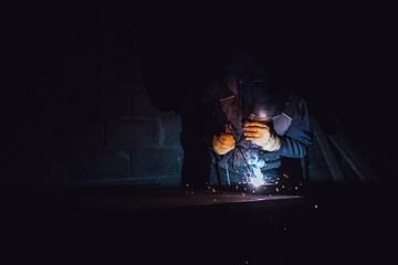 Welder welding a metal plate with an electrode in a factory