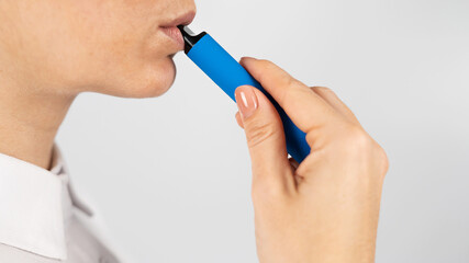 Caucasian woman smokes disposable vape on white background. Alternative device for smoking.