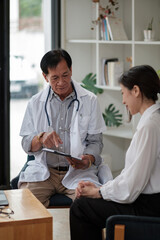 Obraz premium Senior asian doctor physician consulting young female patient, talking to client at medical checkup visit. Geriatric diseases treatment. Elderly medical health care concept.