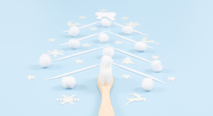 Bamboo toothbrush and a creative Christmas tree made of toothpicks on a soft blue background.