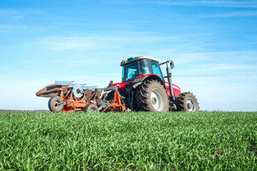 Tractor agricultural machine cultivating field.