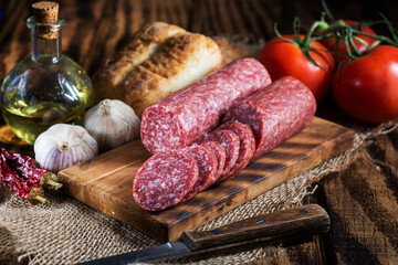 sliced salami on a cutting board with bread and and garlic.