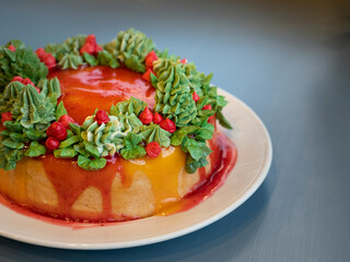 Homemade cake for christmas celebartion decoration with red and green cream like cristmas tree with tasty orange and strawbery sauce. Spot focus.