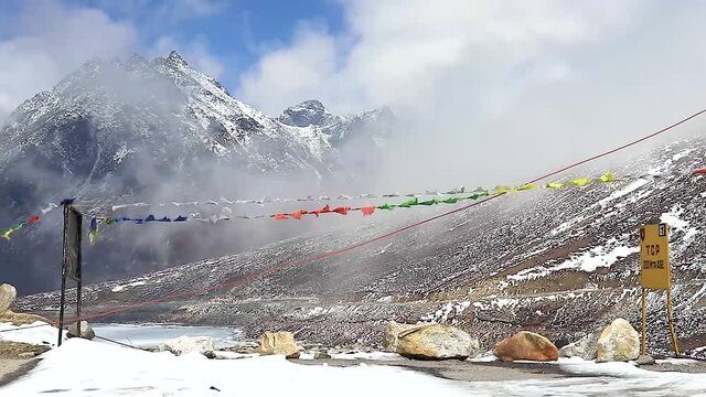 snow cap mountain with dramatic sky through the blurred buddhism flags frame at day video is taken at sela pass tawang arunachal pradesh india.
