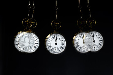 Gold Pocket watch swining hypnotically from chain. Black background