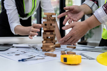 Engineers and architects are playing on wooden game condos on top of desks, comparing playing wooden games to standardized and beautiful building designs. Interior design ideas.