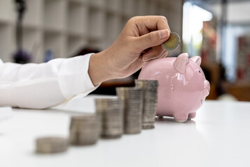 Businesswoman holding a coin in a piggy bank. Placing coins in a row from low to high is comparable to saving money to grow more. The concept of growing savings and saving by investing in stock funds.