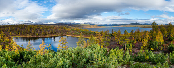 Fototapeta na wymiar Russia. Magadan Region. A beautiful forest lake against the backdrop of the Big Anngachak mountain range. Autumn in the vicinity of Lake Jack London.