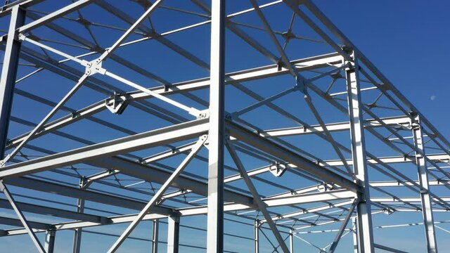 Metal construction - steel frame of unfinished industrial hall. Structure (framework) consisting of iron girders and beams meant to support the roof isolated against blue sky on a sunny day.