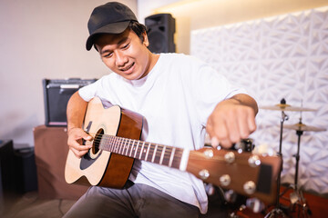 Obraz premium a male vocalist laughs with friends while tuning an acoustic guitar