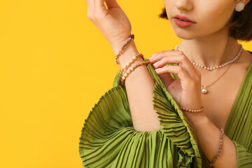 Woman touching elegant bracelet on color background, closeup - obrazy, fototapety, plakaty