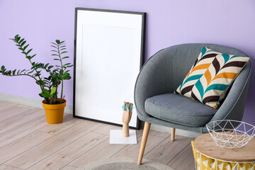 Blank frame with houseplant and grey armchair near lilac wall
