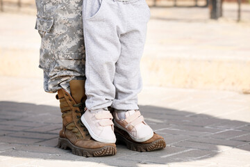 Feet of female soldier with her little daughter outdoors