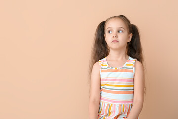 Portrait of cute little girl with ponytails on beige background