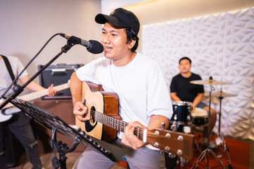 Fototapeta premium Handsome vocalist smiles for the camera while singing while playing acoustic guitar