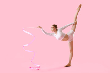 Beautiful young woman doing gymnastics with ribbon on color background