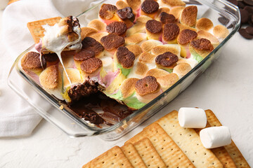 Baking dish with tasty S'mores dip and crackers on white background, closeup