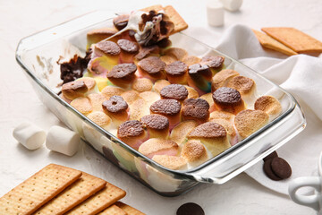 Baking dish with tasty S'mores dip and crackers on white background, closeup