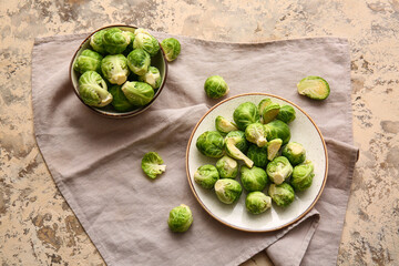 Bowl and plate with fresh Brussels cabbage on color background