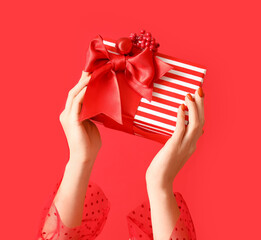 Hands with Christmas gift box on red background