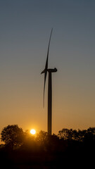 Obraz premium A wind turbine. The generator and base of the wind turbines. Renewable energy. Electrical windmills. General contest of green energy. Turbine working at sunrise. Warm colors