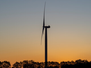 Fototapeta na wymiar A wind turbine. The generator and base of the wind turbines. Renewable energy. Electrical windmills. General contest of green energy. Turbine working at sunrise. Warm colors