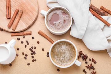 Cups of tasty coffee with cinnamon and beans on beige background