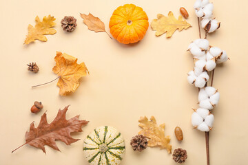 Frame made of autumn composition with cotton flowers and pumpkins on beige background
