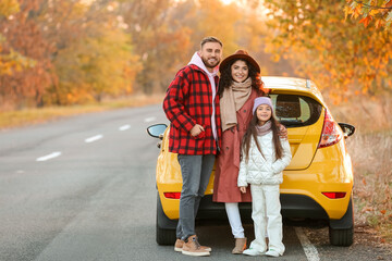 Parents with little daughter and cute dog near yellow car on autumn day