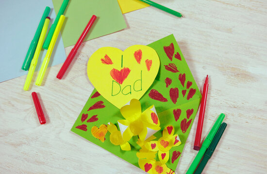 Greeting card for on Father's Day heart with lettering. Envelope  crafts and flower from colorful paper. Handmade. DIY concept. little girl prepared a surprise for dad