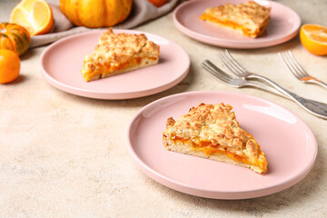 Plates with pieces of tasty pumpkin pie on light background