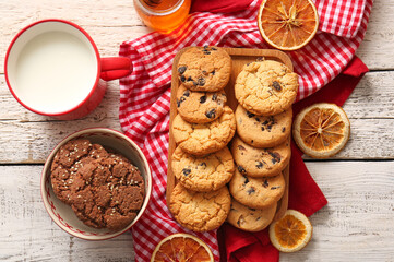Board and bowl with tasty homemade cookies on white wooden background