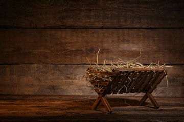 Manger with hay on wooden background