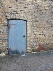 Gray wooden door in a brick wall, selective focus