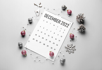 Paper calendar for December 2022 and Christmas decor on light background