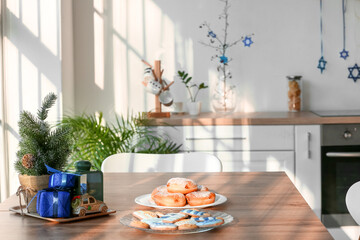 Tasty desserts and decorations for Hanukkah celebration on table in kitchen