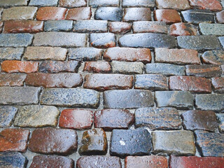 wet pavement paved with multi-colored stone, selective focus