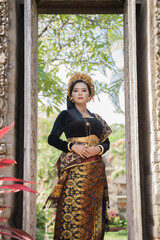 Fototapeta na wymiar Beautiful woman wearing traditional Balinese kebaya and woven cloth standing