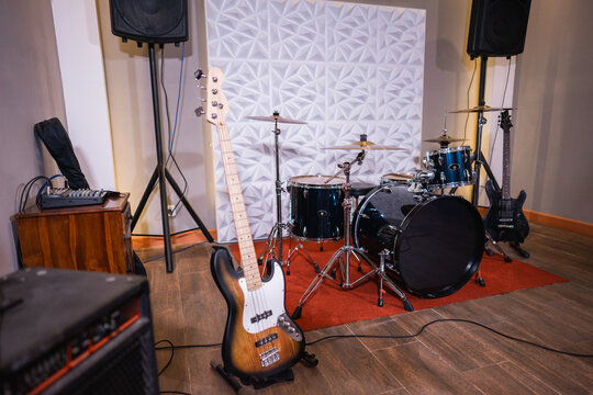 a room with a drum kit and electric bass guitar as well as a sound system
